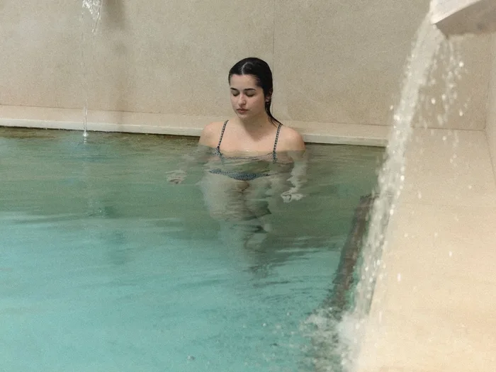 Una usuària a la piscina termal, al costat de la cascada d'aigua