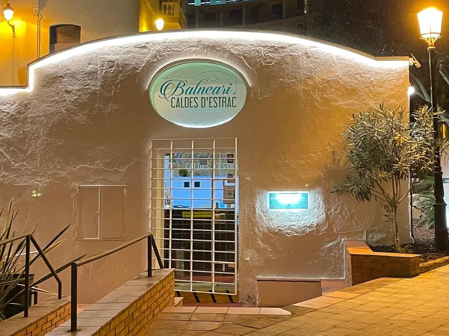 L'entrada del Balneari de Caldetes il·luminada de nit, amb el rètol oval