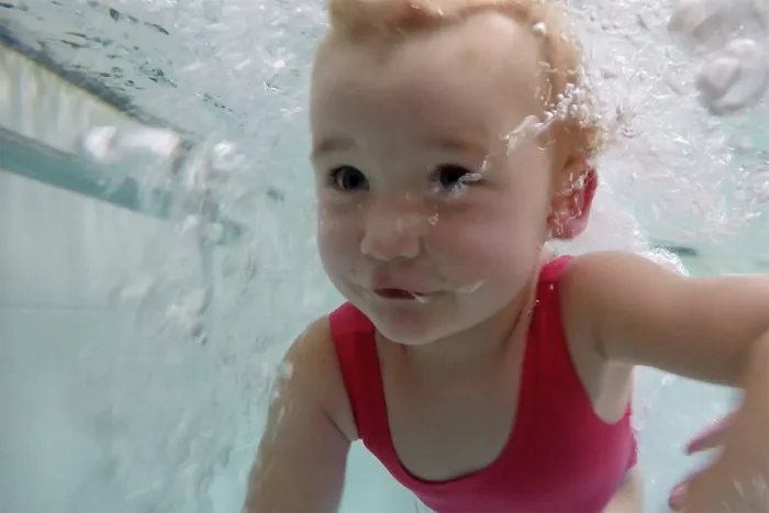 Infant gaudint de l'aigua de la piscina termal
