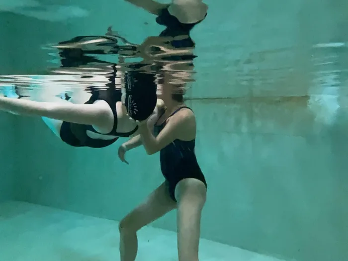 Sessió de fisioteràpia aquàtica: la fisioterapeuta sosté la usuària a la piscina termal