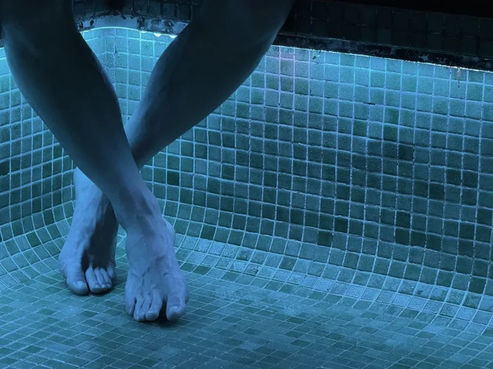 Cames dins la piscina termal, amb el mosaic blau al fons